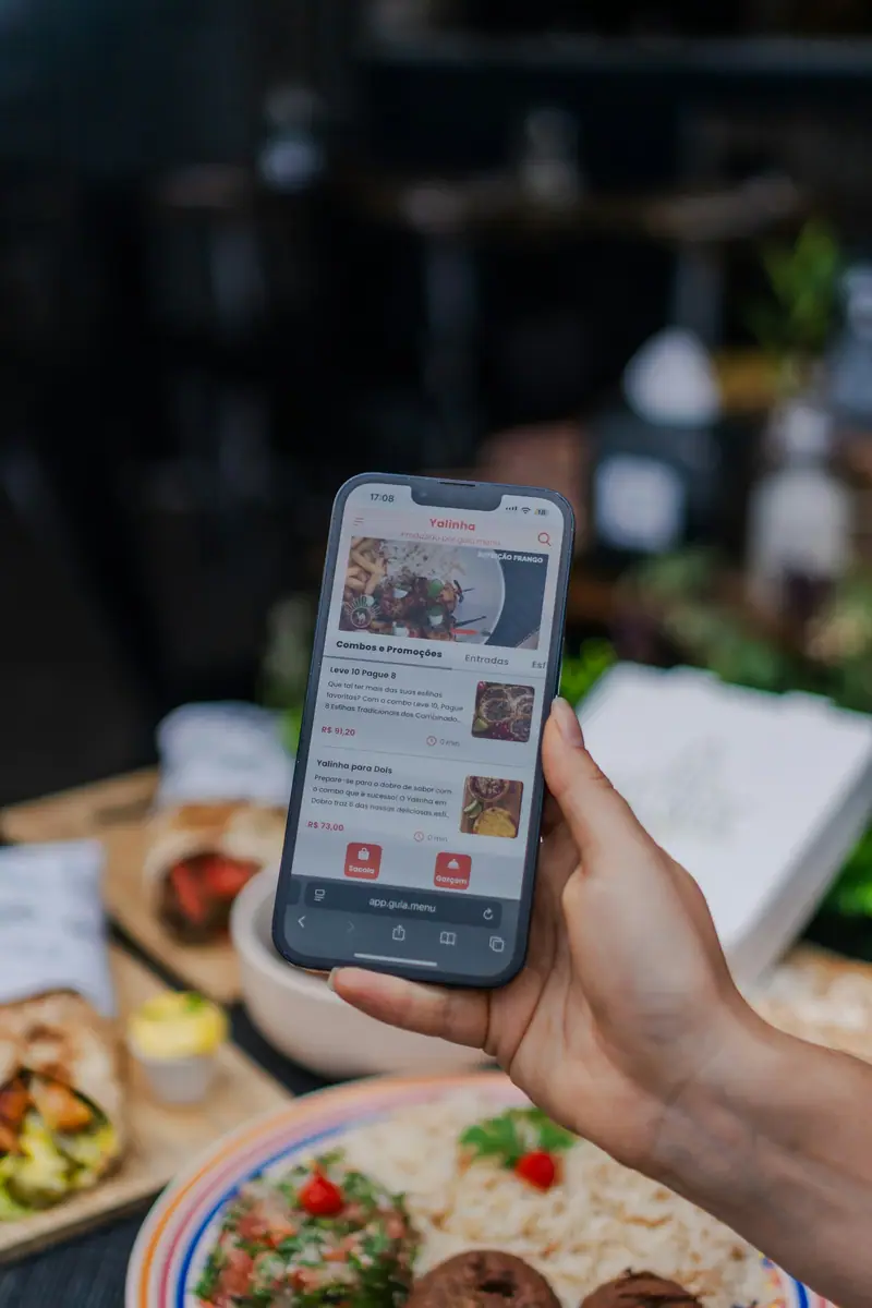 Celular na mão com o cardápio digital aberto e os pratos listados